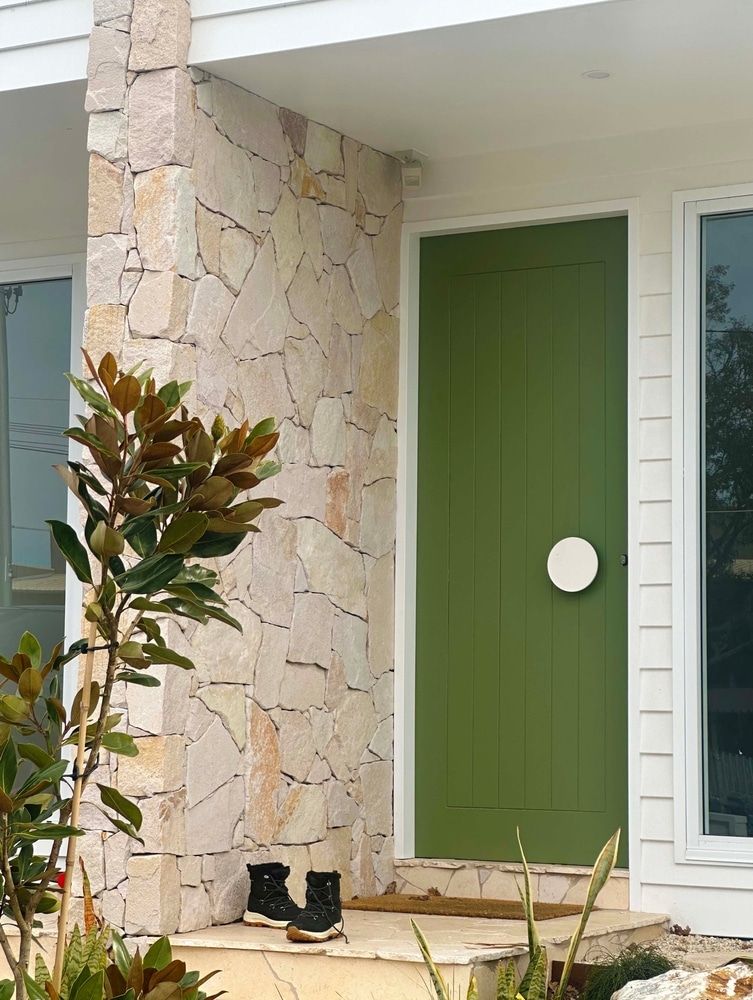 Modern house entrance with green door, stone wall, large windows and plants—classic style for Mortgage Broker Gold Coast clients.