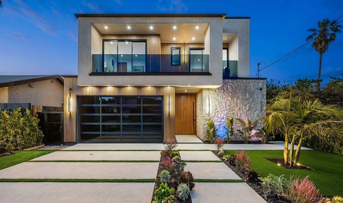 Contemporary two-storey home at dusk with large windows, balcony, and palm trees—ideal for a Mortgage Broker Gold Coast client.
